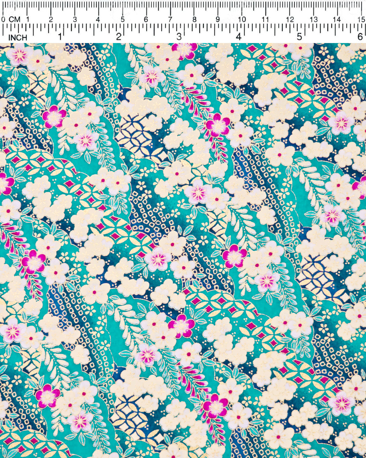 Japanese chiyogami paper featuring cream and magenta pink plum blossoms and cream, magenta pink, and teal wisteria on a teal blue background with metallic gold details, shown next to a ruler for size reference.