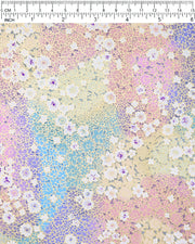 Japanese chiyogami paper featuring small white and pastel rainbow-colored flowers with metallic gold details, shown next to a ruler for size reference.