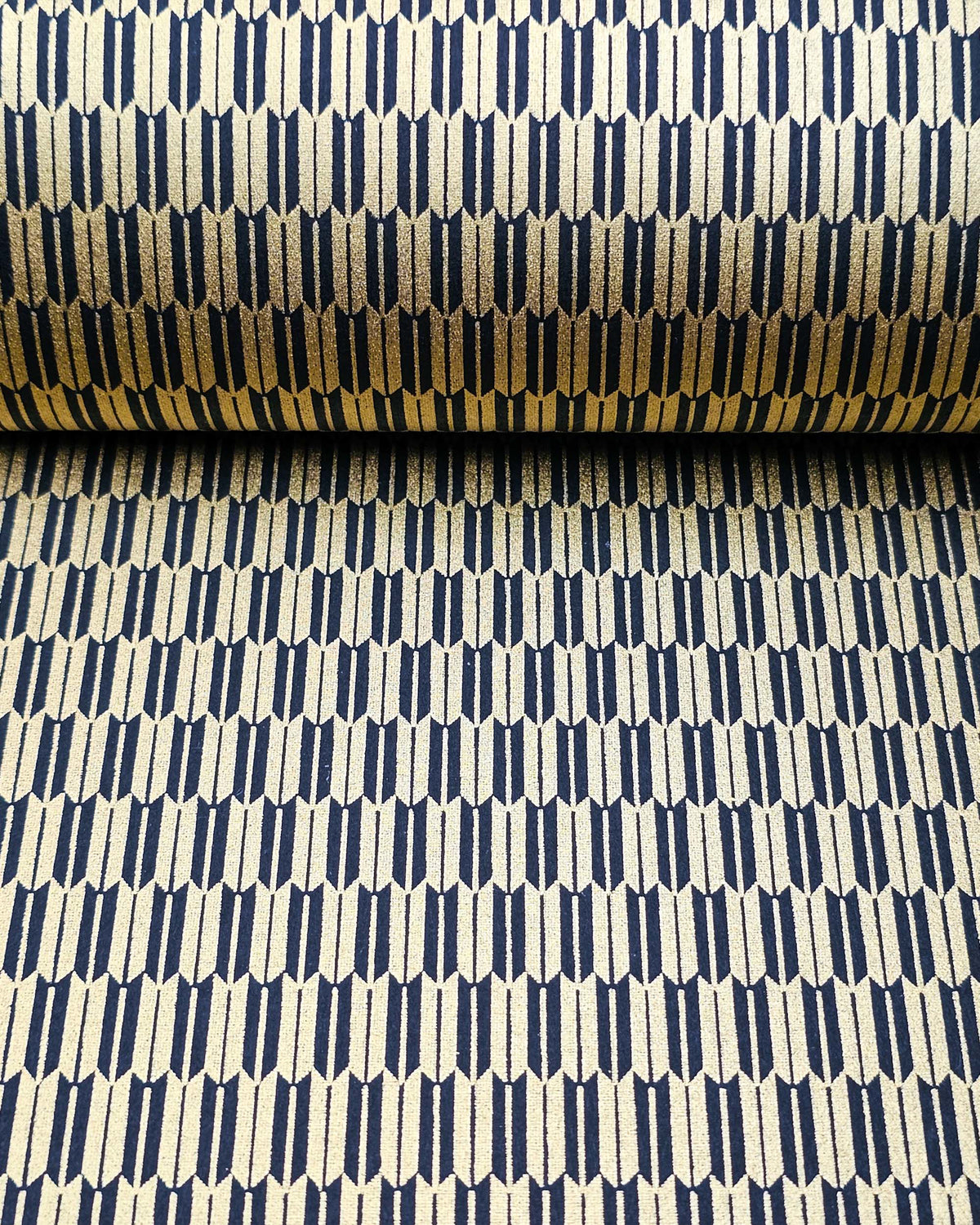 Japanese chiyogami paper featuring a traditional black and metallic gold yagasuri (arrow feather) pattern, shown rolled to highlight the design.