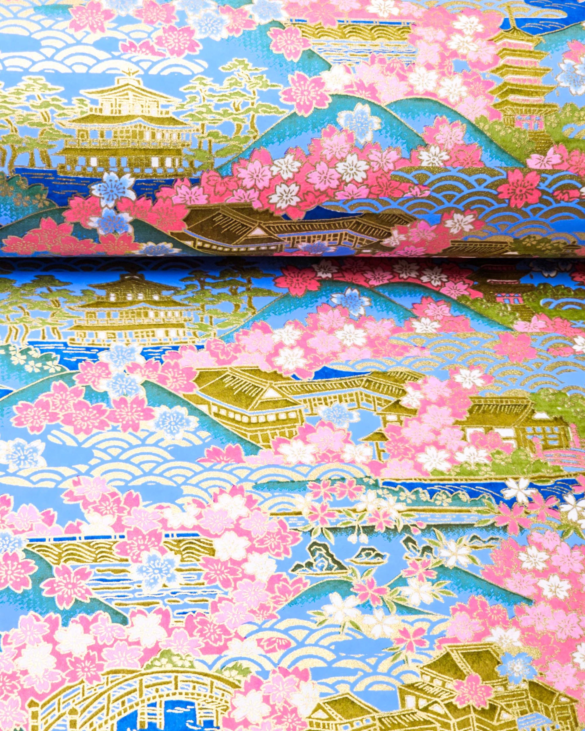 Japanese chiyogami paper featuring a blue and pink cherry blossom-filled Japanese village with metallic gold accents.