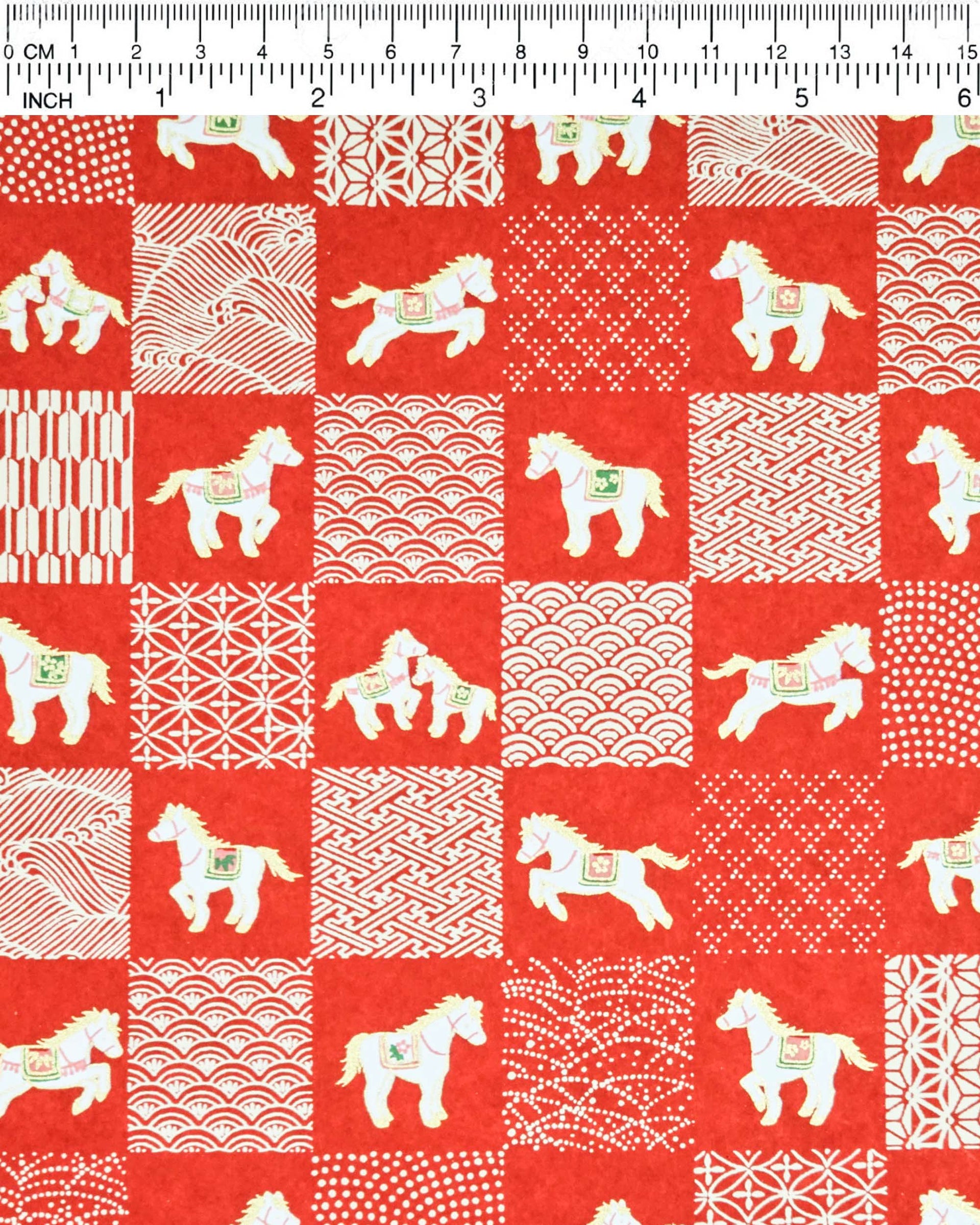Japanese chiyogami paper featuring white horses with red and green accents and white assorted traditional Japanese designs in an ichimatsu (checker) design on a red background with metallic gold accents.