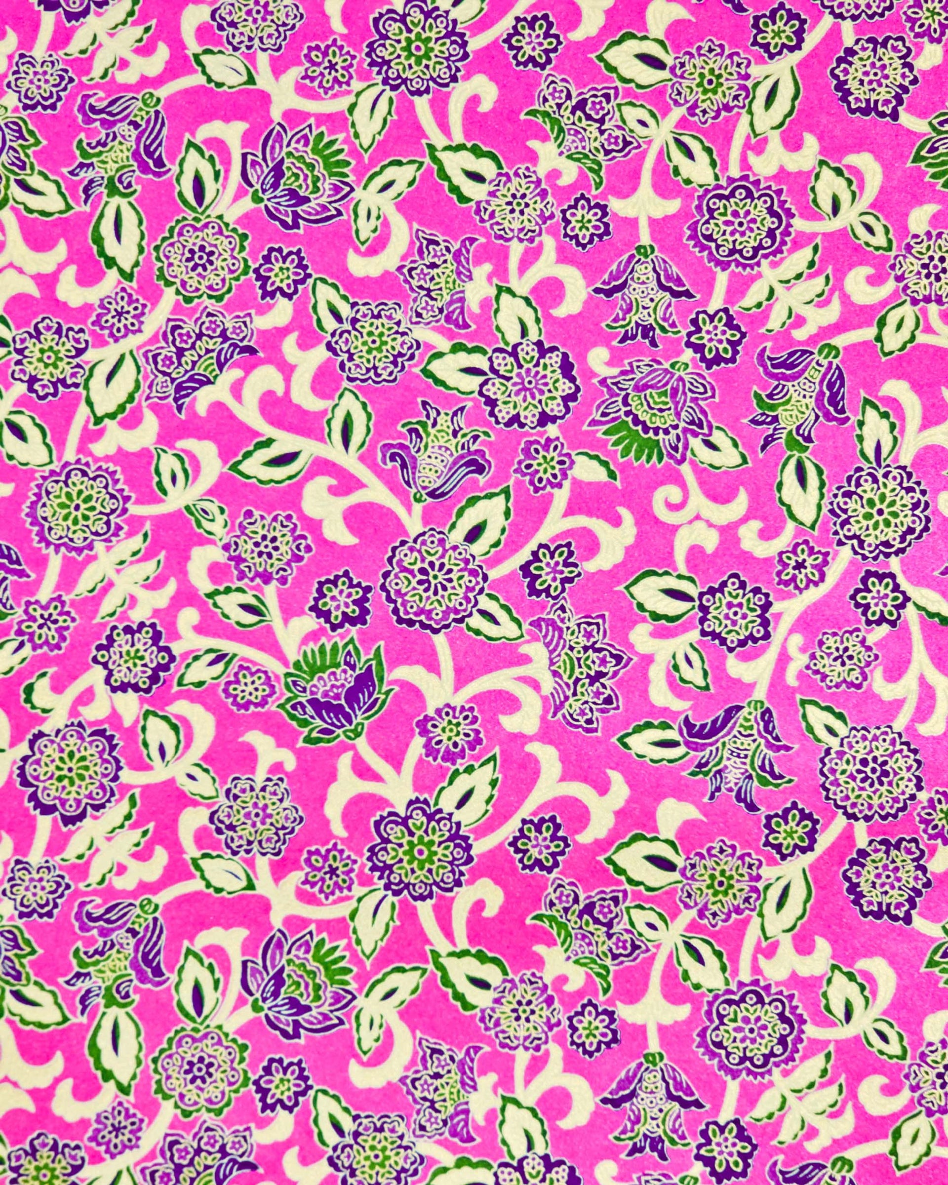 Japanese chiyogami paper featuring green and purple sarasa flowers on a pearlescent magenta pink background with metallic gold accents.