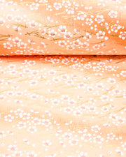 Japanese chiyogami paper featuring small white plum blossoms and matsuba (pine needles) on an orange gradient background with metallic gold accents.