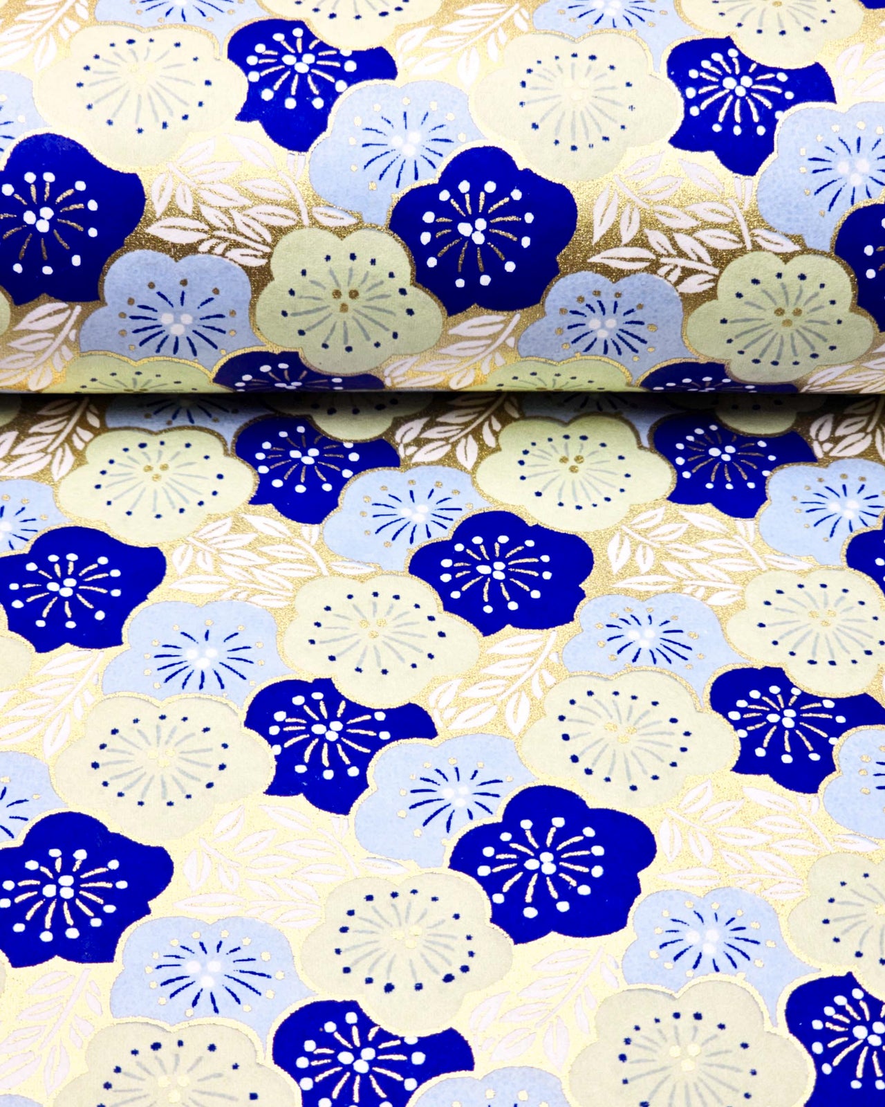 Japanese chiyogami paper featuring large dark blue, light blue, and off-white plum blossoms on a metallic gold background.