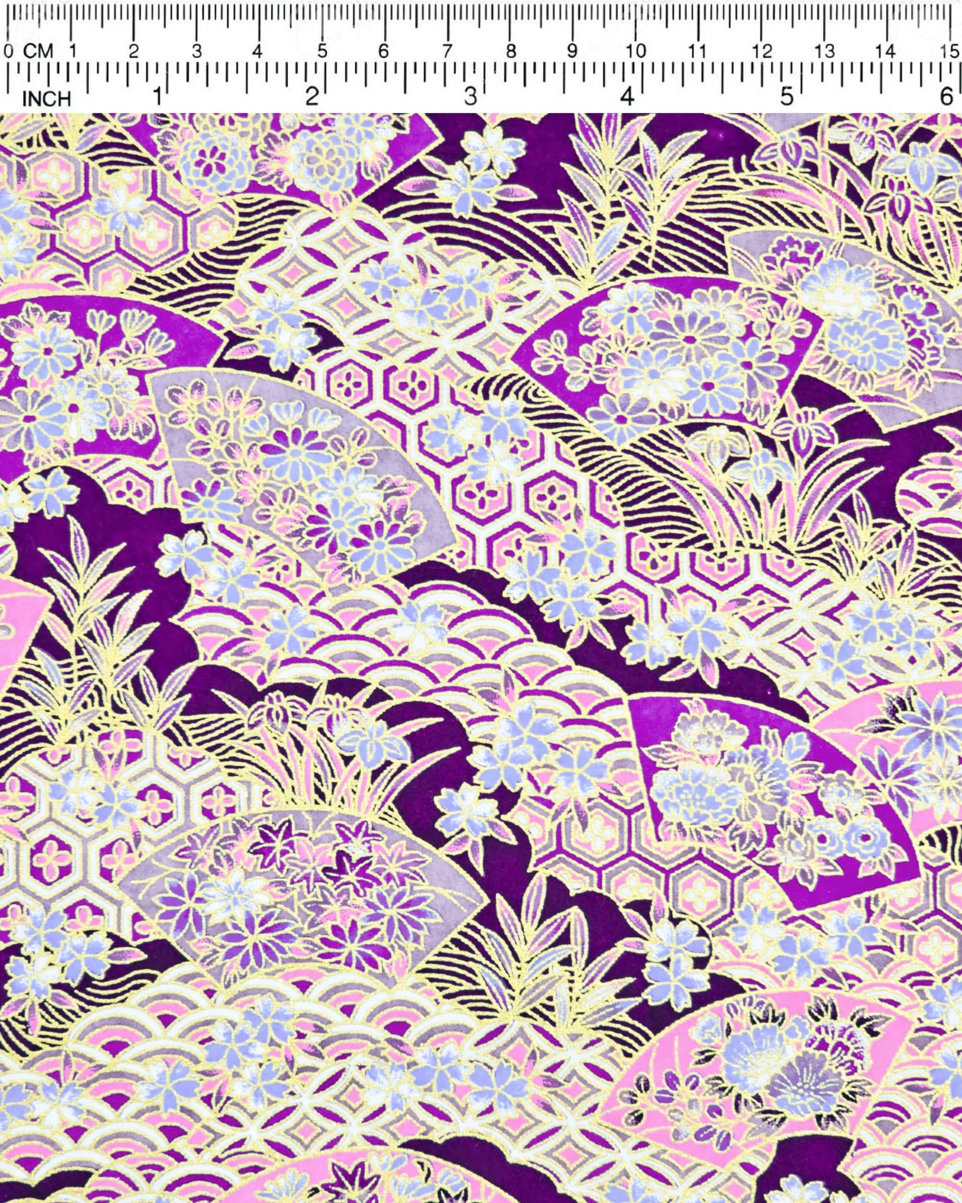 Japanese chiyogami paper featuring purple and pink floral hand fans and various traditional Japanese geometric motifs (shippo, kikko, seigaiha) on a dark purple background with metallic gold accents. Small purple and white cherry blossom are scattered throughout the design.