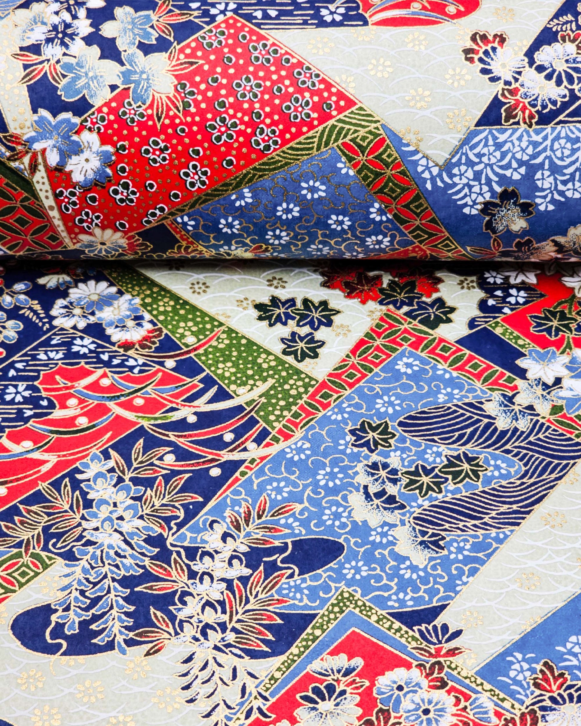 Japanese chiyogami paper featuring red, blue, off white, and green patches adorned with an assortment of various floral and geometric patterns with metallic gold details.