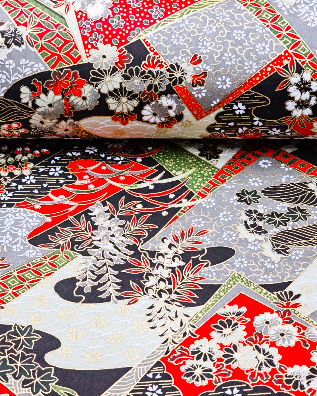Japanese chiyogami paper featuring red, gray, black, off white, and green patches adorned with an assortment of various floral and geometric patterns with metallic gold details.