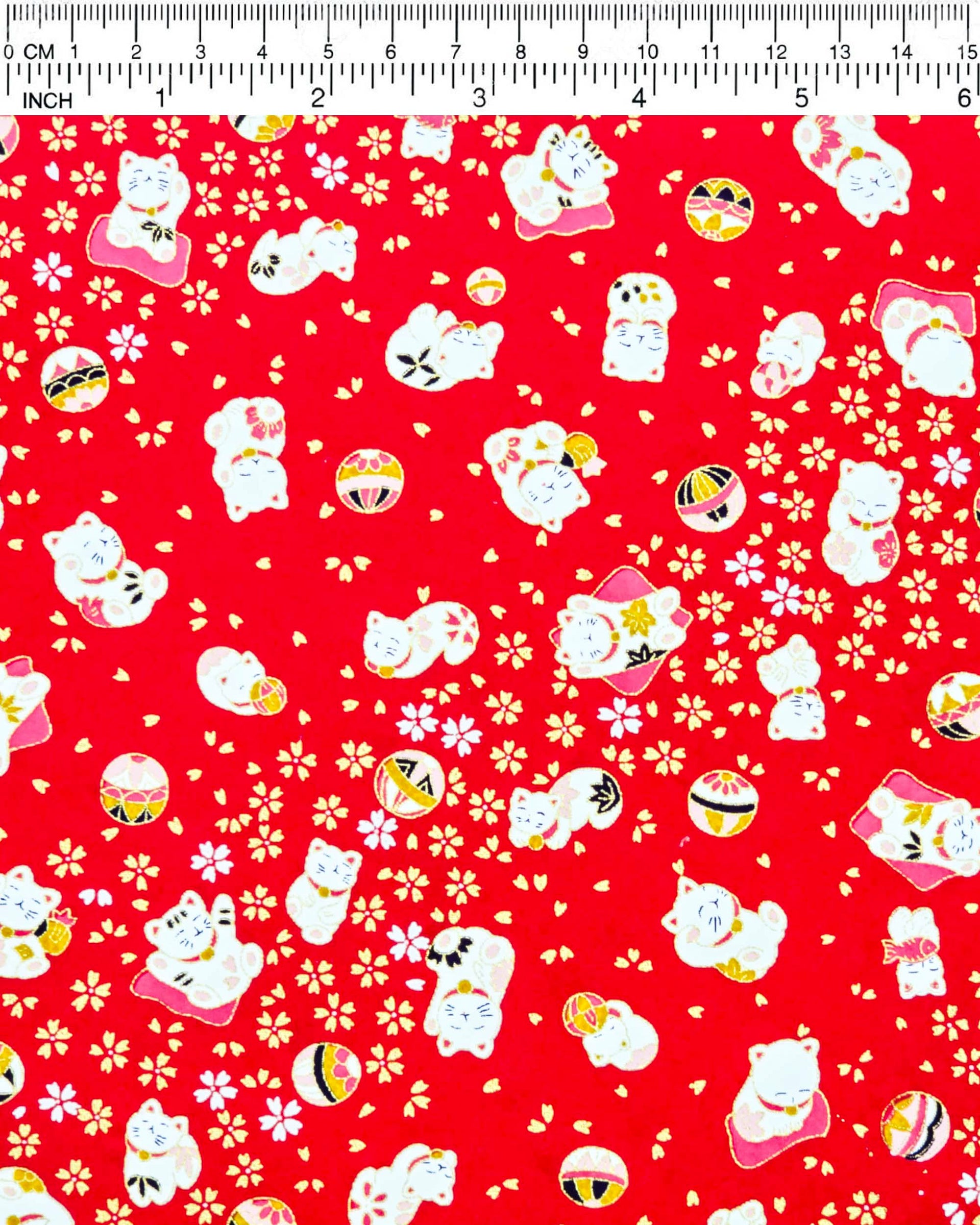 Japanese chiyogami paper featuring assorted white and red Maneki Neko (lucky cats) with small white and gold cherry blossoms and temari balls on a bright red background with metallic gold details.