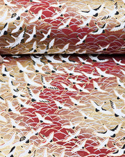 Japanese chiyogami paper featuring white flying cranes in a zigzag formation on a brown background with metallic gold and silver details.