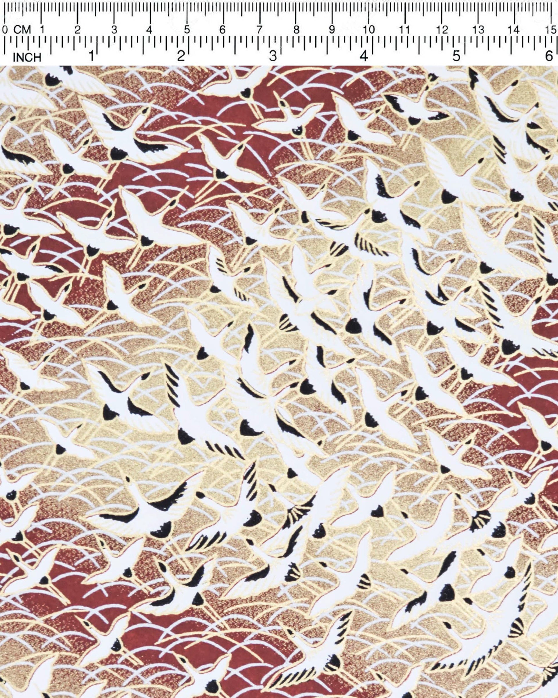 Japanese chiyogami paper featuring white flying cranes in a zigzag formation on a brown background with metallic gold and silver details.