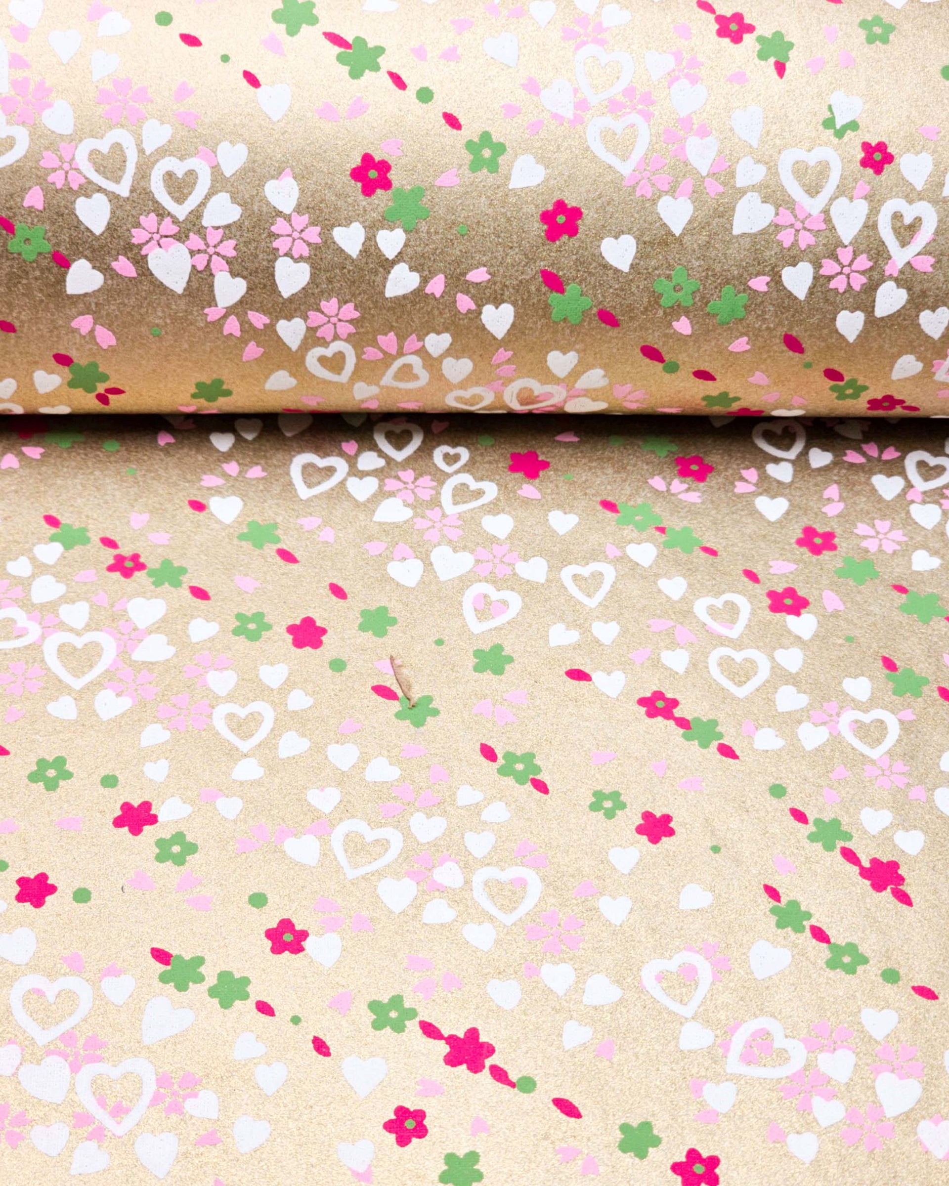 Japanese chiyogami paper featuring white hearts, small red and green flowers, and pink cherry blossoms on a metallic gold background.