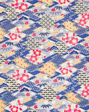 Japanese chiyogami paper featuring large pearlescent magenta pink and white plum blossoms, blue and gold bamboo leaves, and light blue and gold pine on a blue and gold background with metallic gold accents. The background is adorned with a various traditional Japanese geometric designs.