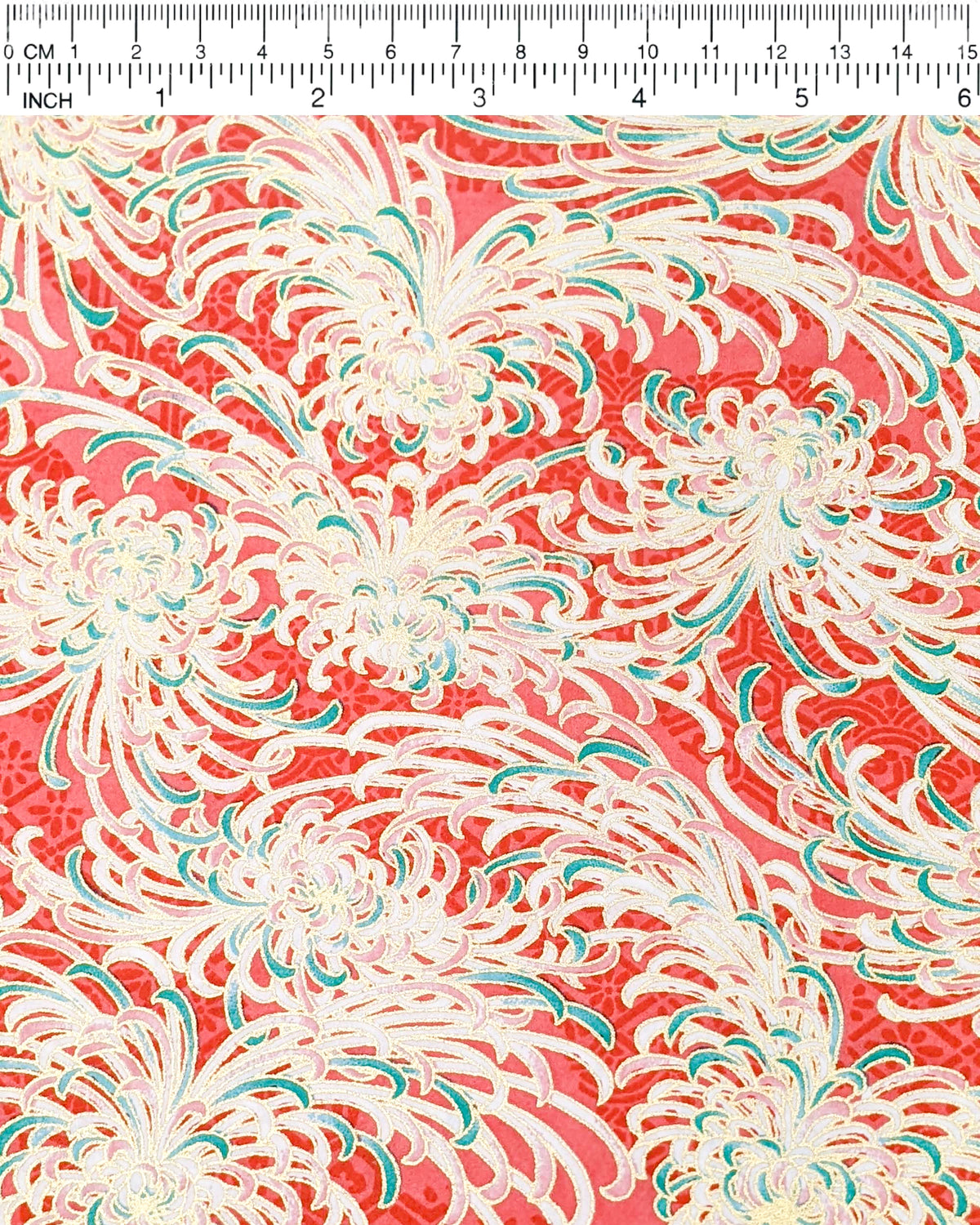 Japanese chiyogami paper featuring red, green, and white chrysanthemums on a red background with metallic gold details, shown next to a ruler for size reference.