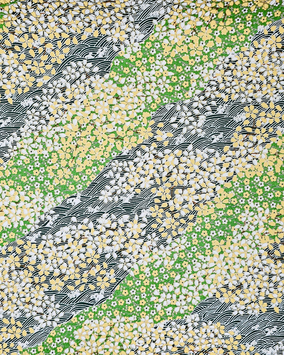 Japanese chiyogami paper featuring white and yellow cherry blossoms on a light green background and a dark green and white wave (aranami) pattern with metallic gold details. 
