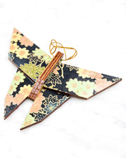 Large wooden origami butterfly ornament featuring assorted green, pink, beige, and gray maple leaves with dark gray and metallic gold dotted maple leaves on a dark gray background.