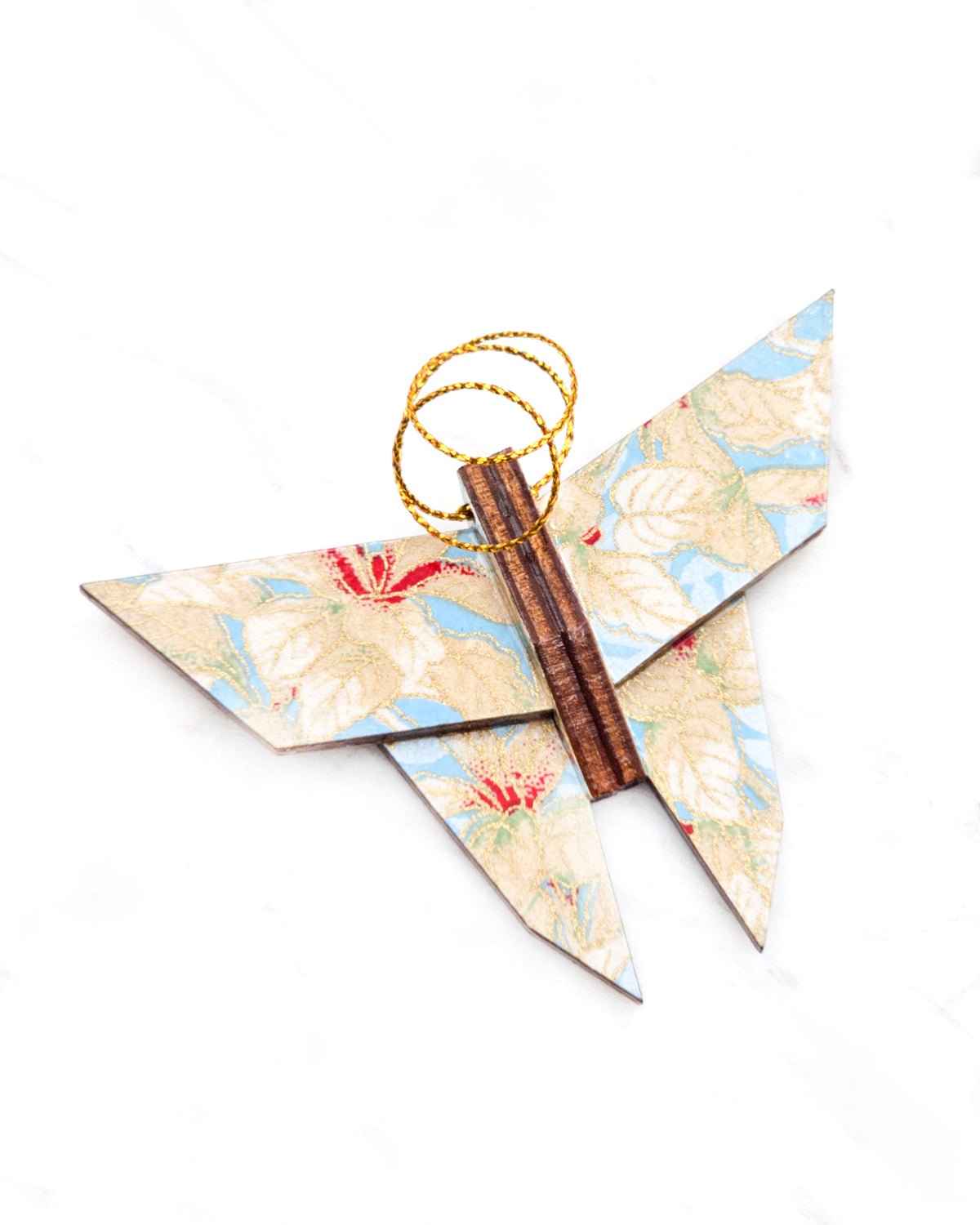 Small wooden origami butterfly ornament featuring beige and white leaves on a light blue background with metallic gold details.