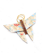 Small wooden origami butterfly ornament featuring beige and white leaves on a light blue background with metallic gold details.