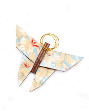 Small wooden origami butterfly ornament featuring beige and white leaves on a light blue background with metallic gold details.