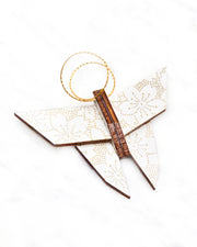Small wooden origami butterfly ornament featuring metallic gold pointillistic cherry blossoms on a white background.