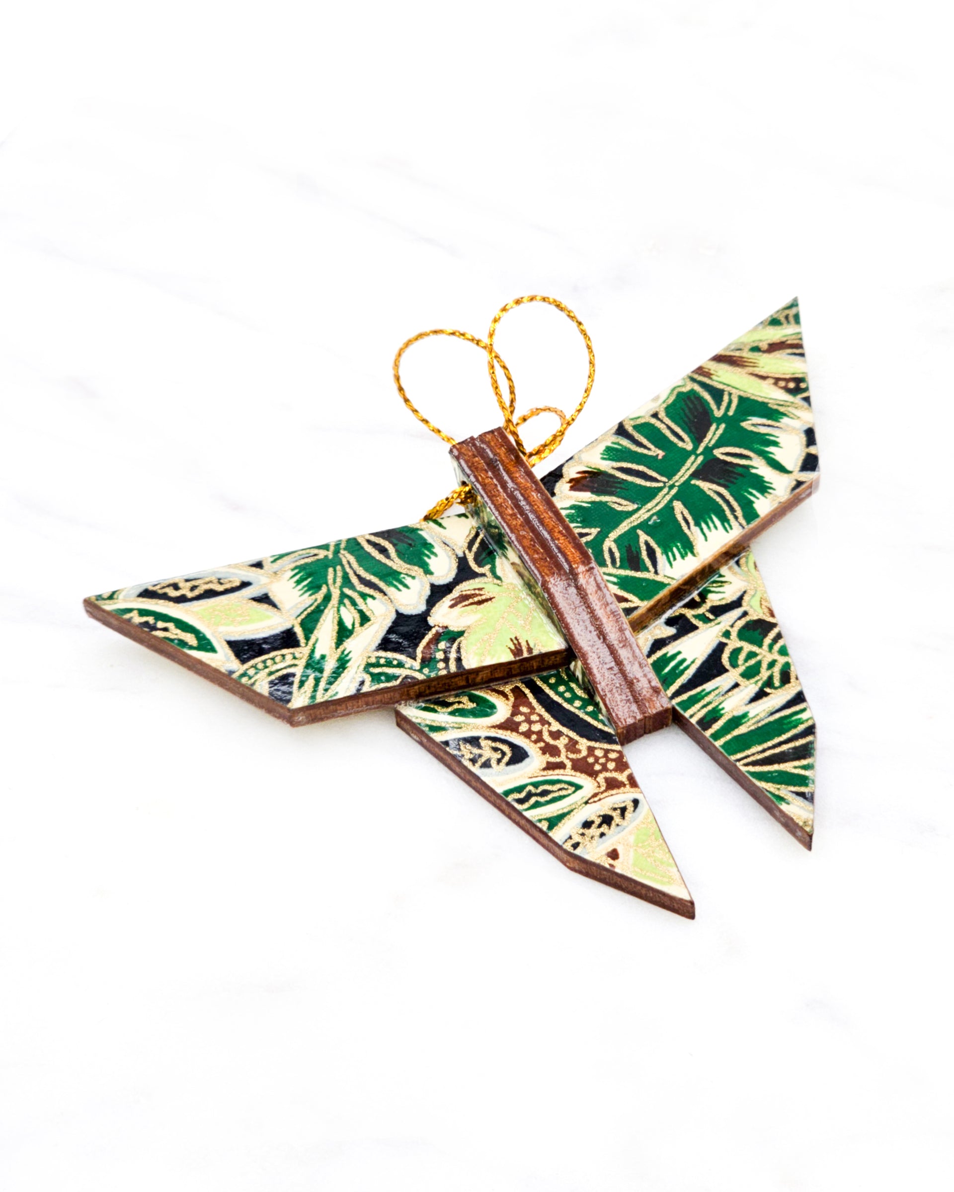 Small wooden origami butterfly ornament featuring green and brown frond leaves on a black background with metallic gold details.