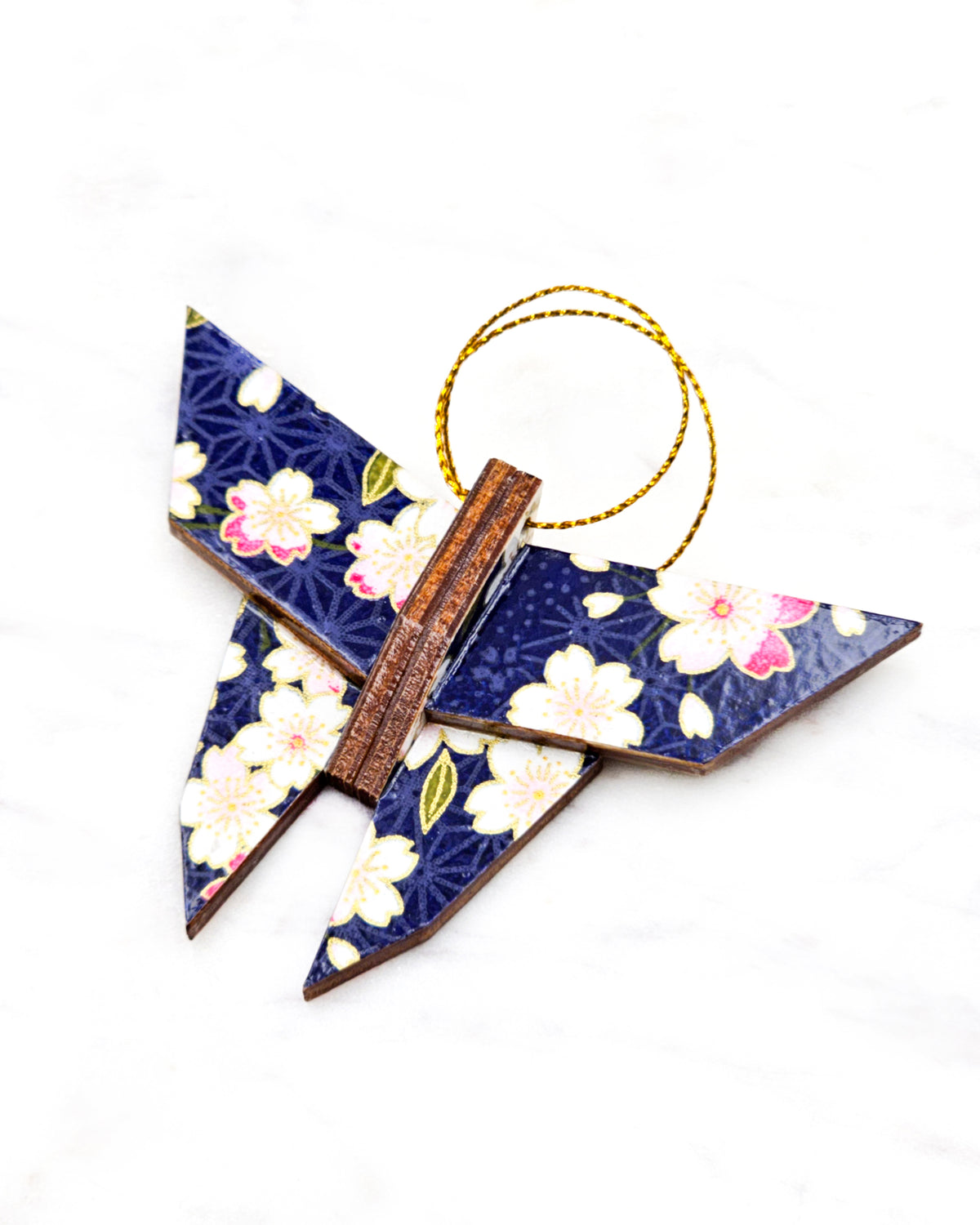 Small wooden origami butterfly ornament featuring pink and white cherry blossoms on a dark blue background with metallic gold details.