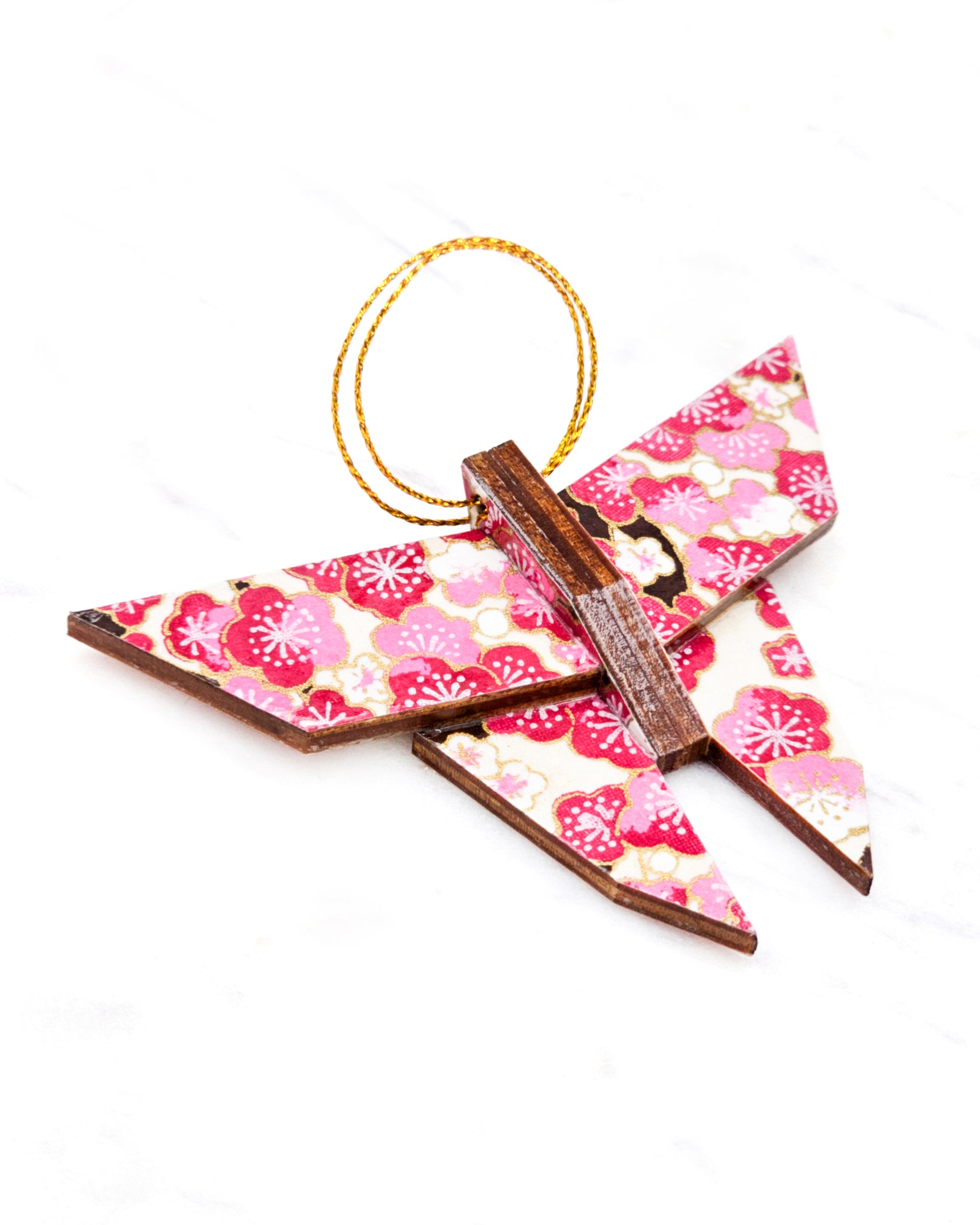 Small wooden origami butterfly ornament featuring pink and white plum blossoms with dark brown branches on a white background with metallic gold details.