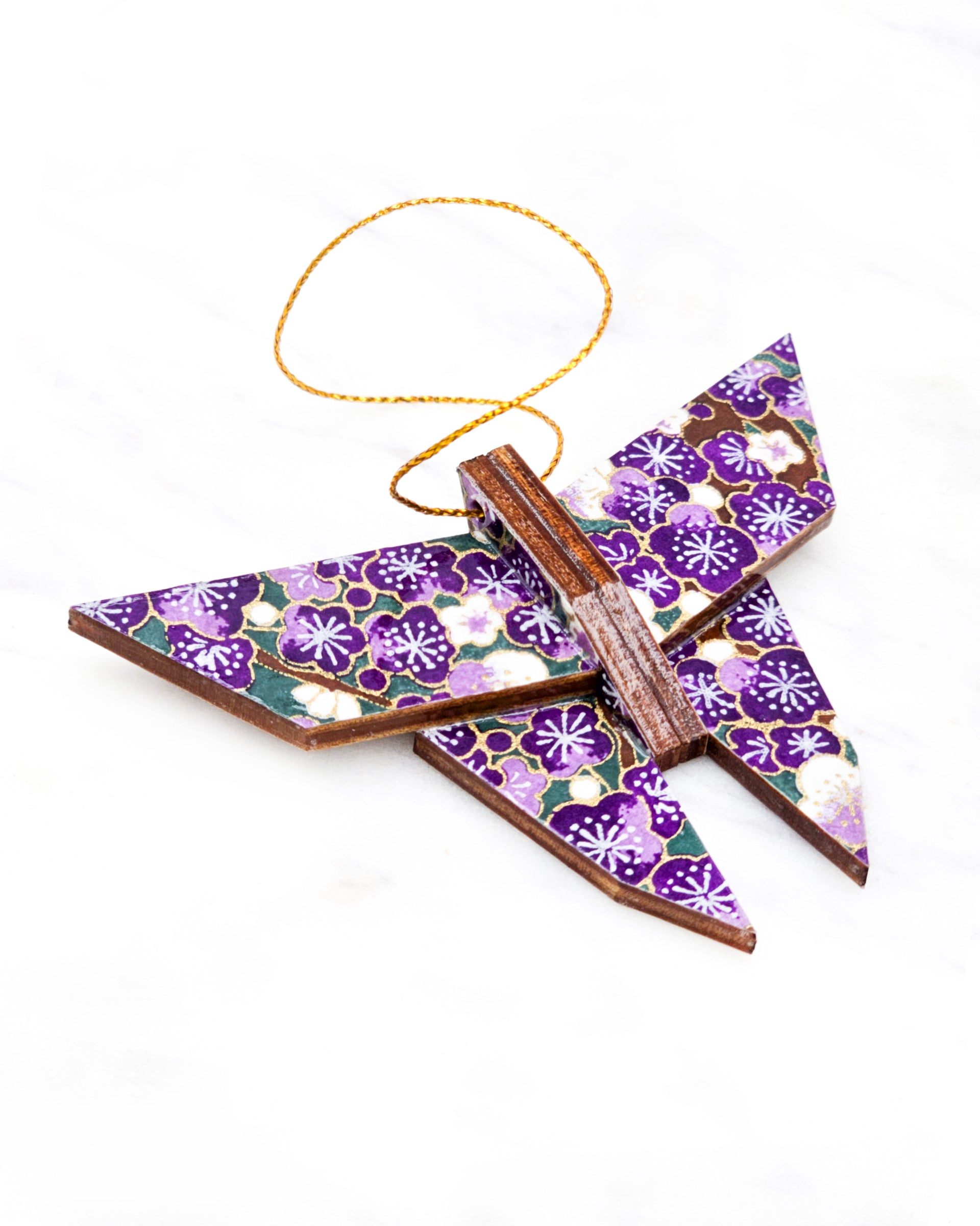 Small wooden origami butterfly ornament featuring purple and white plum blossoms with dark brown branches on a green background with metallic gold details.