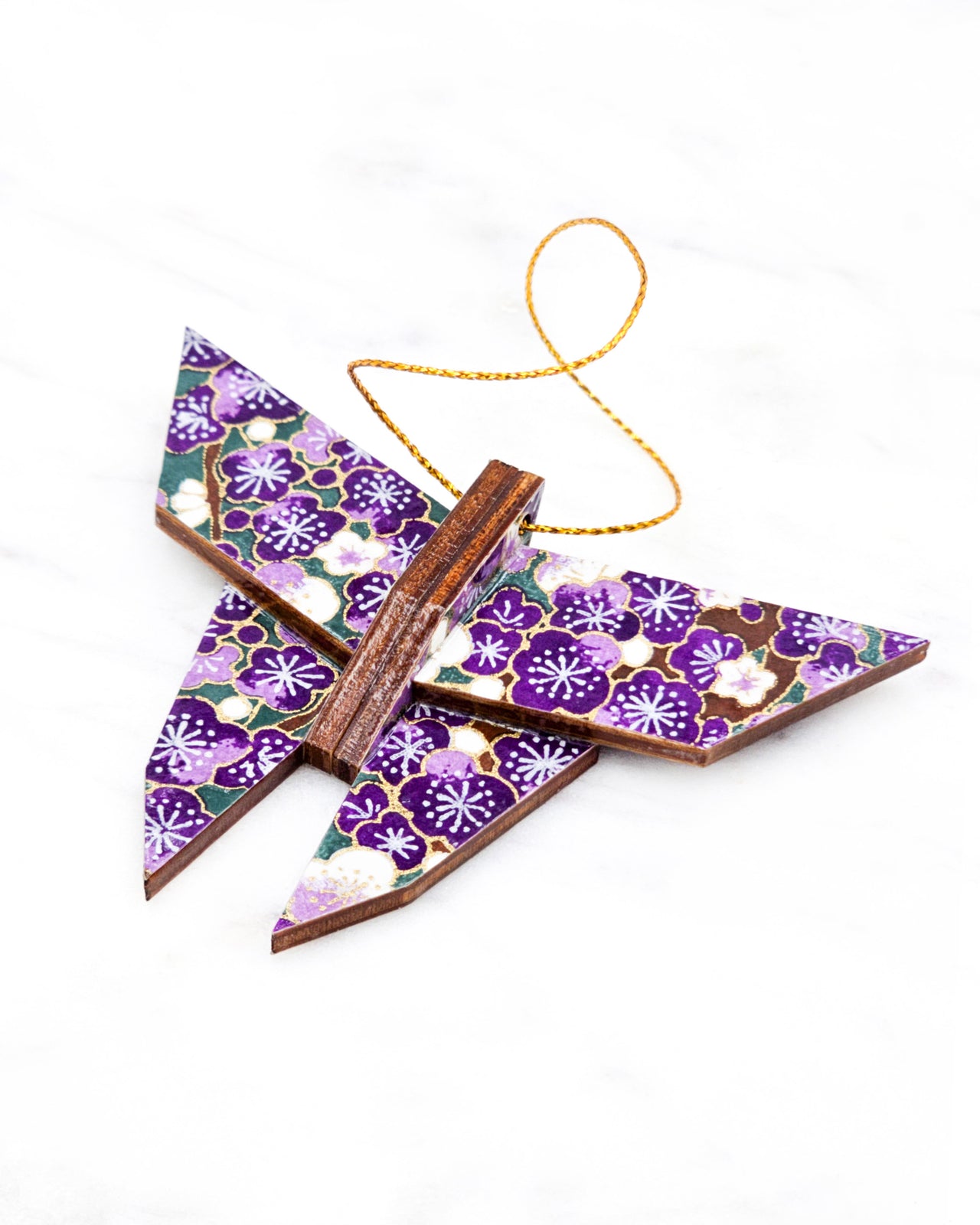 Small wooden origami butterfly ornament featuring purple and white plum blossoms with dark brown branches on a green background with metallic gold details.