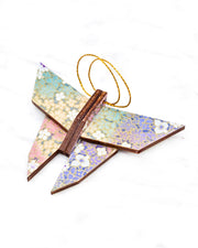 Small wooden origami butterfly ornament featuring small rainbow-colored flowers with metallic gold details.