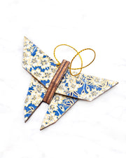 Small wooden origami butterfly ornament featuring white cherry blossoms on a blue background with metallic gold details.