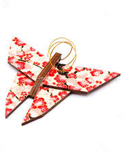 Wooden origami butterfly ornament featuring red plum blossoms on a light cream background with metallic gold accents.