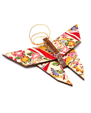 Wooden origami butterfly ornament featuring red floral ribbons on a beige background.