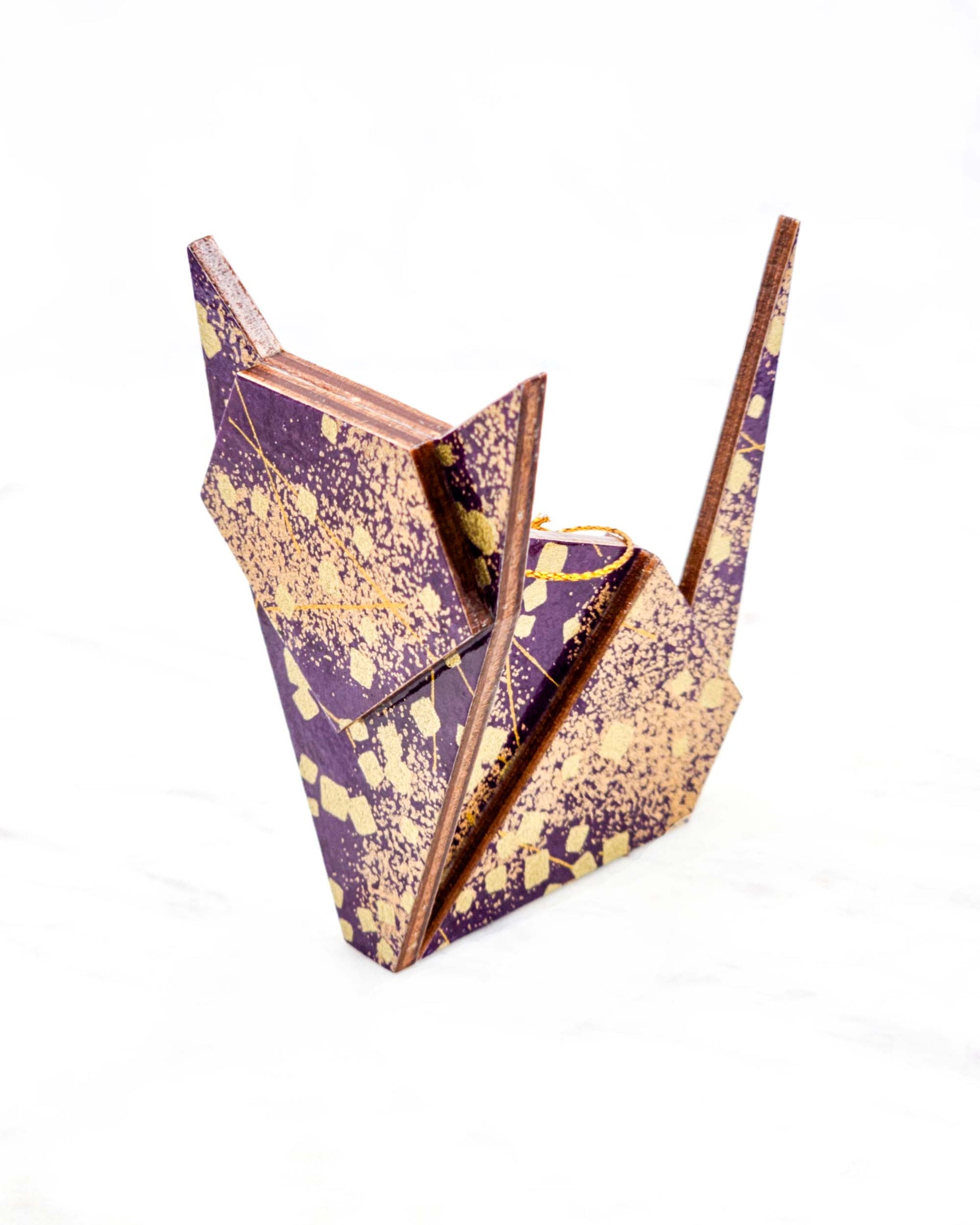 Large wooden origami cat ornament featuring scattered metallic gold geometric shapes and fine gold lines on a dark purple background.