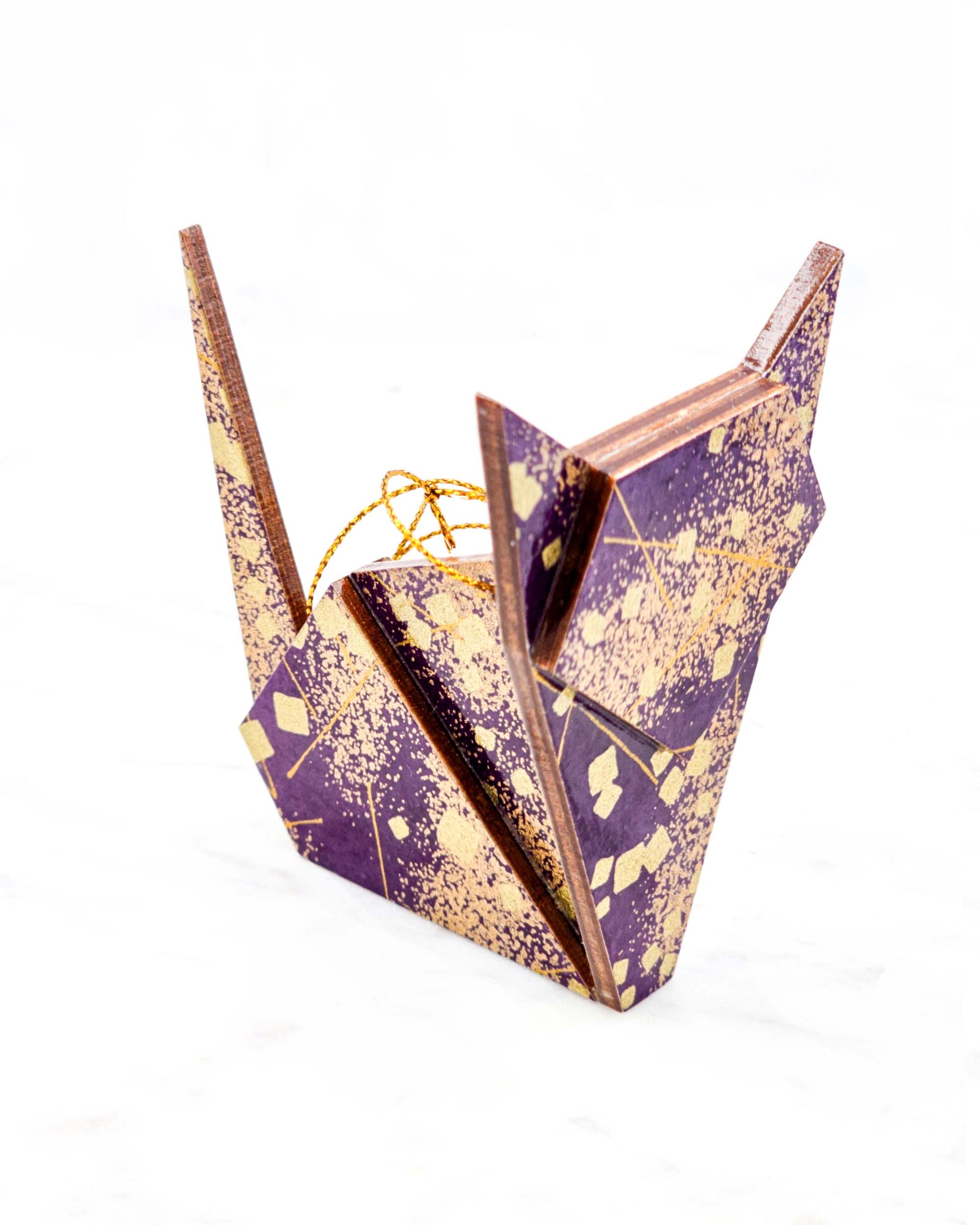 Large wooden origami cat ornament featuring scattered metallic gold geometric shapes and fine gold lines on a dark purple background.