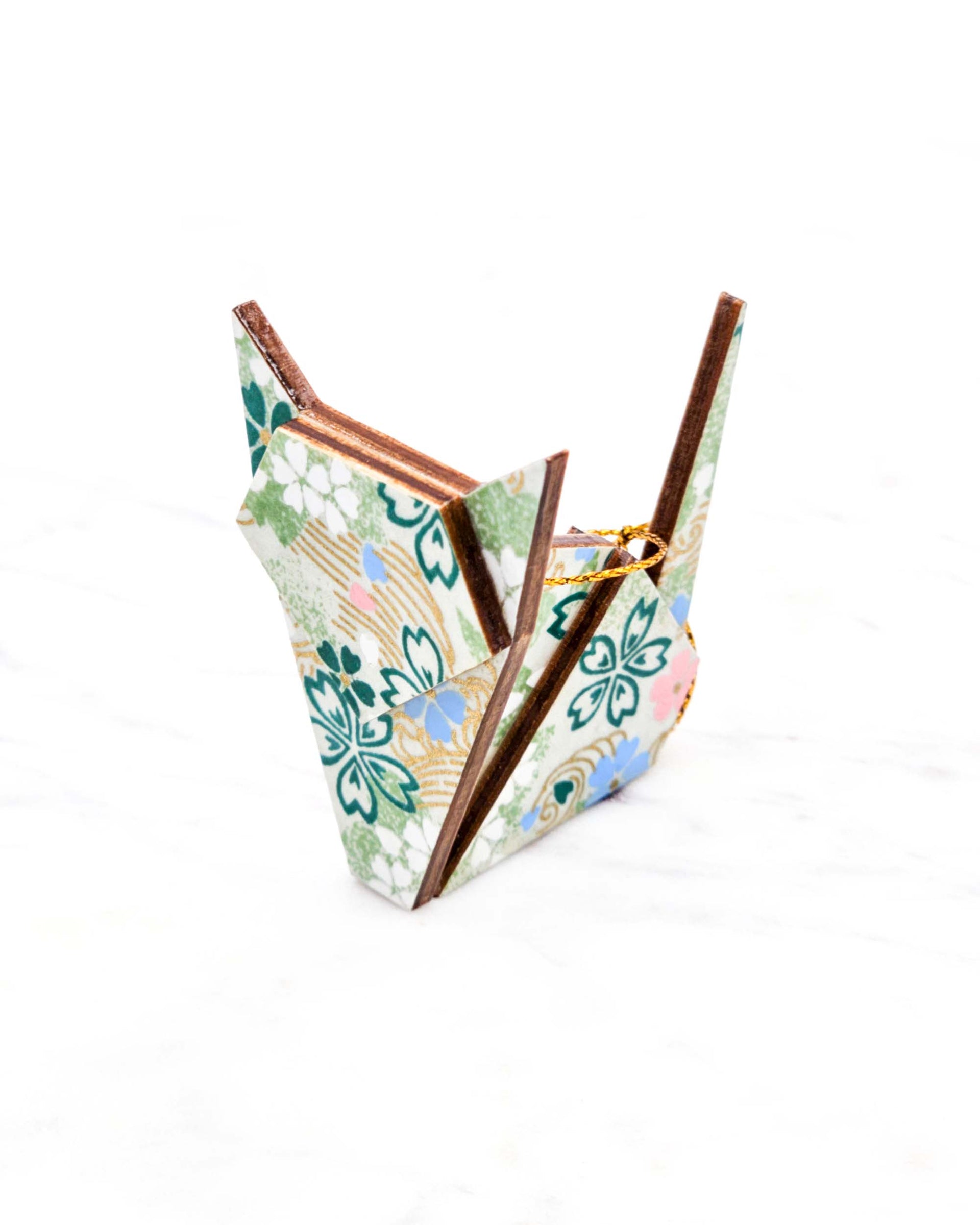 Small wooden origami cat ornament featuring green, white, blue, and pink cherry blossoms on a green background with metallic gold details.