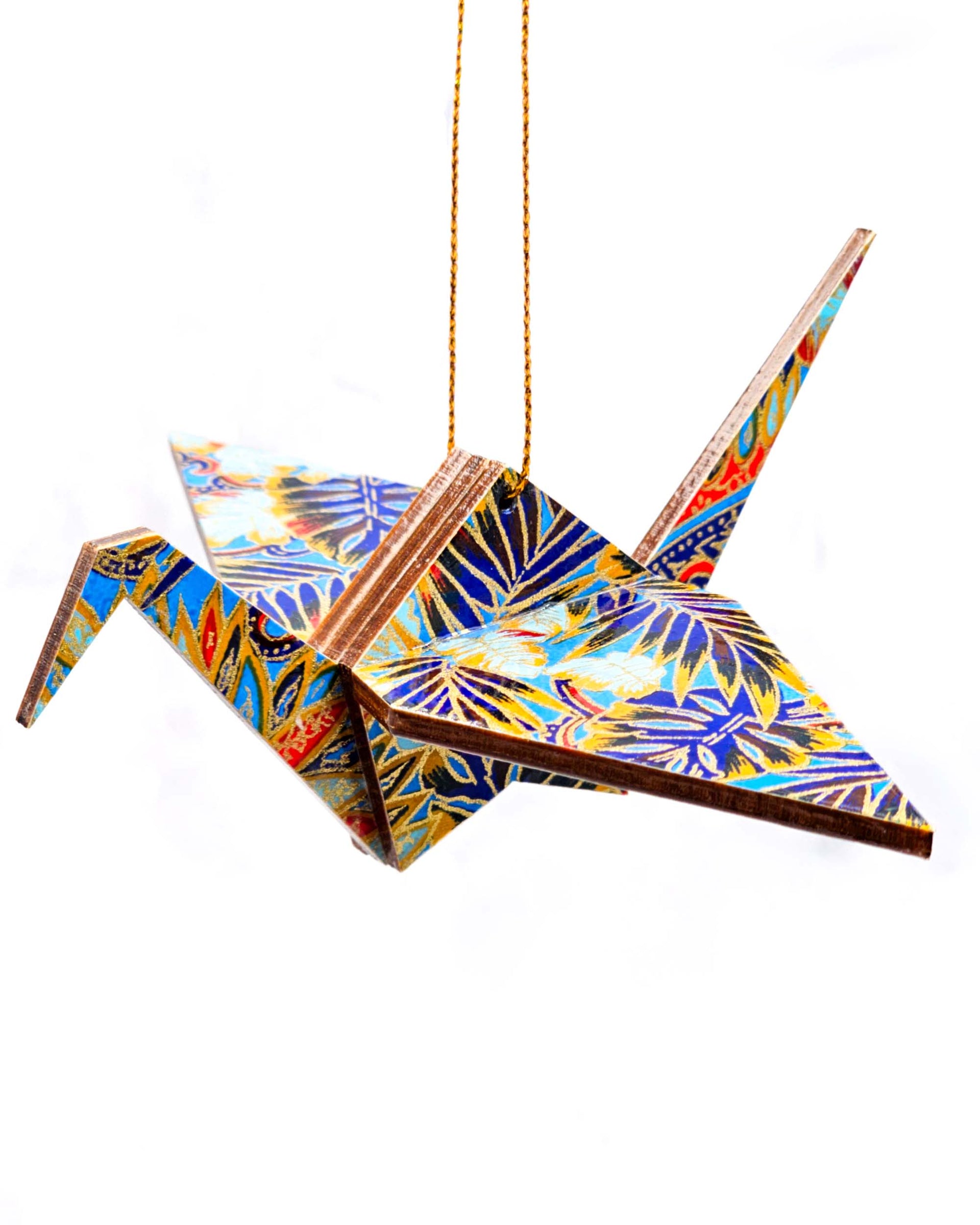 Wooden origami crane ornament featuring blue and red frond leaves on a blue background.