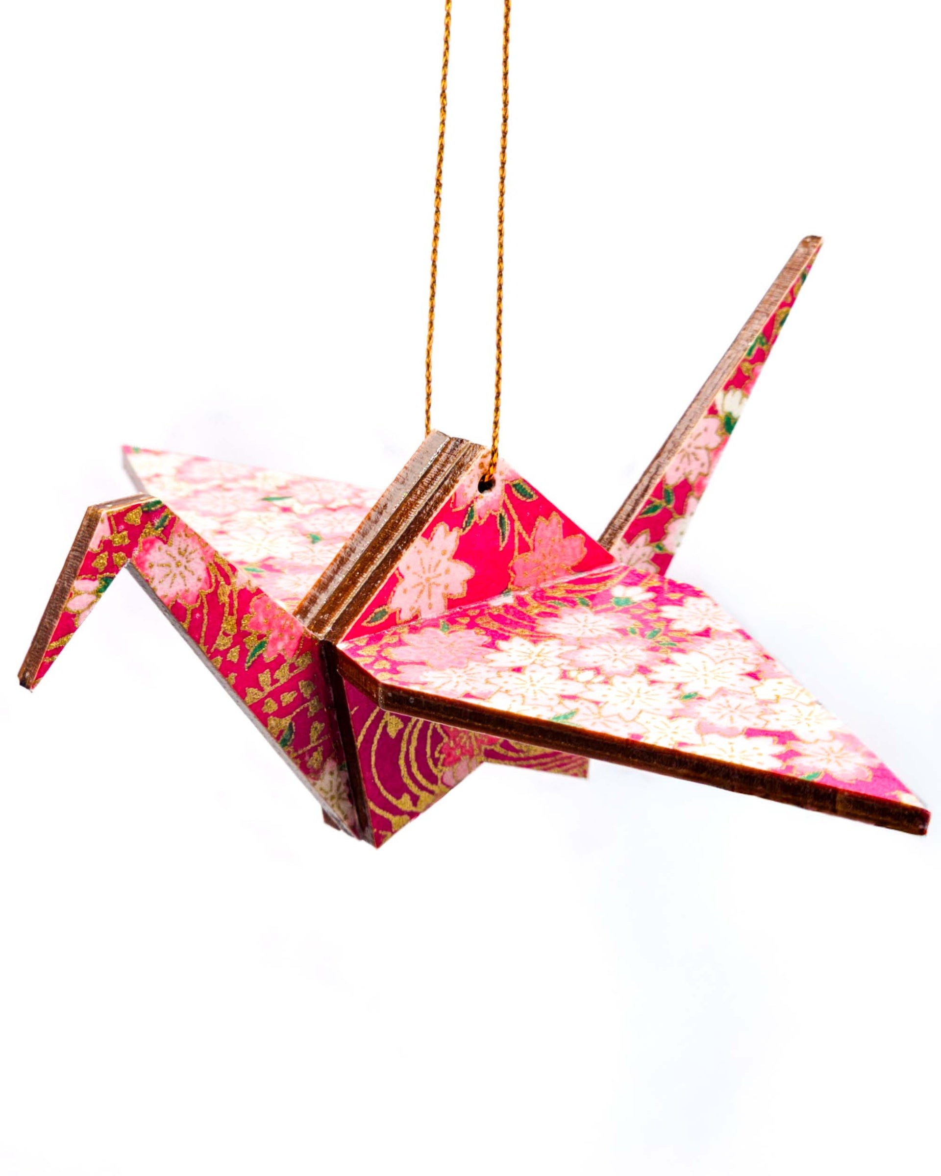 Wooden origami crane ornament featuring pink and white cherry blossoms on a magenta pink background with metallic gold accents.