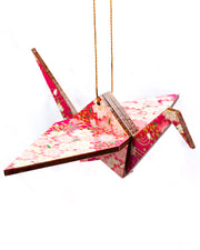 Wooden origami crane ornament featuring pink and white cherry blossoms on a magenta pink background with metallic gold accents.