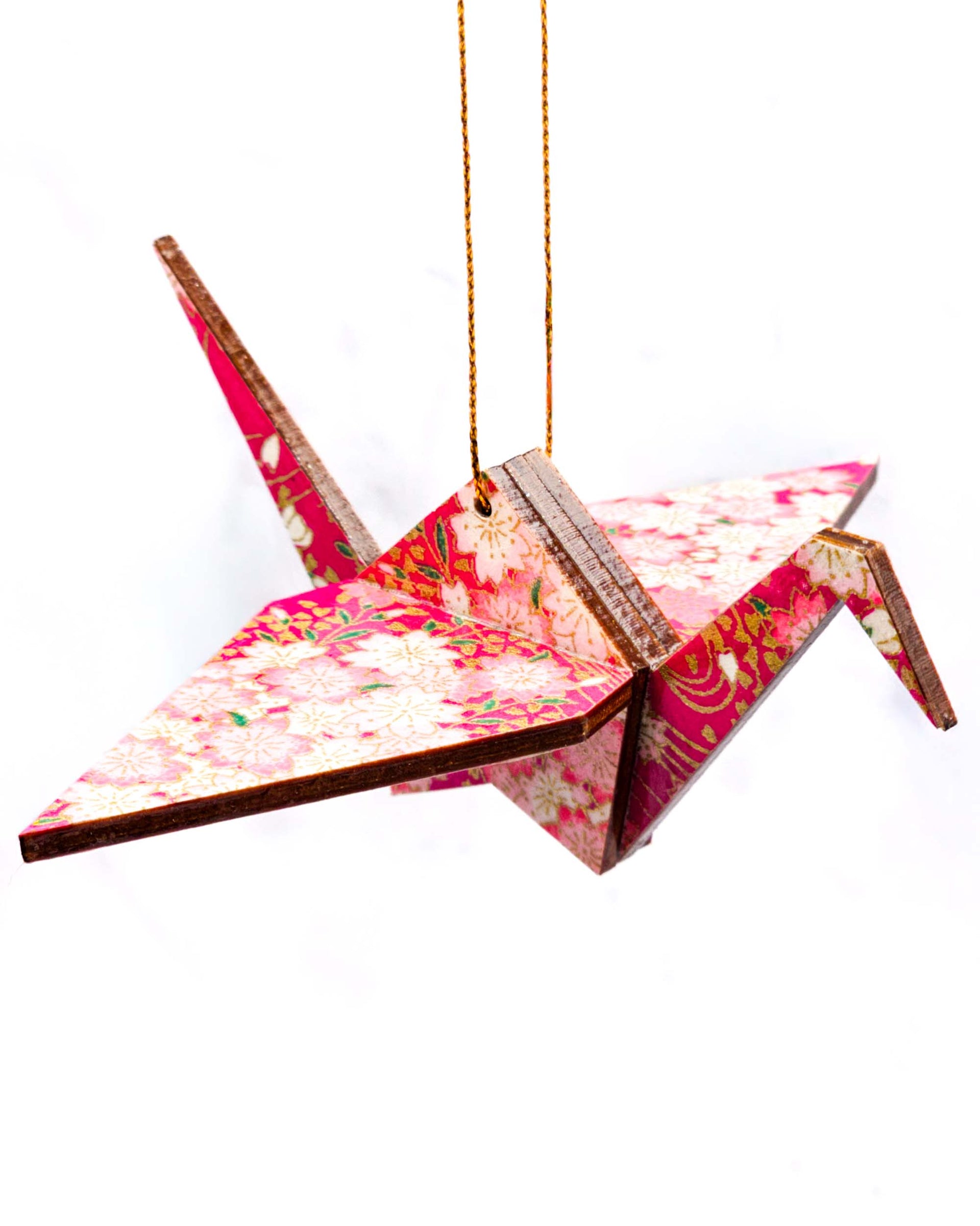Wooden origami crane ornament featuring pink and white cherry blossoms on a magenta pink background with metallic gold accents.