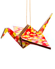 Wooden origami crane ornament featuring pink and yellow plum blossoms on a red background with metallic gold accents.