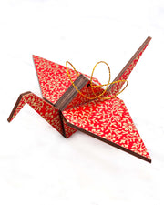 Large wooden origami crane ornament featuring a metallic gold floral motif on a bright red background.