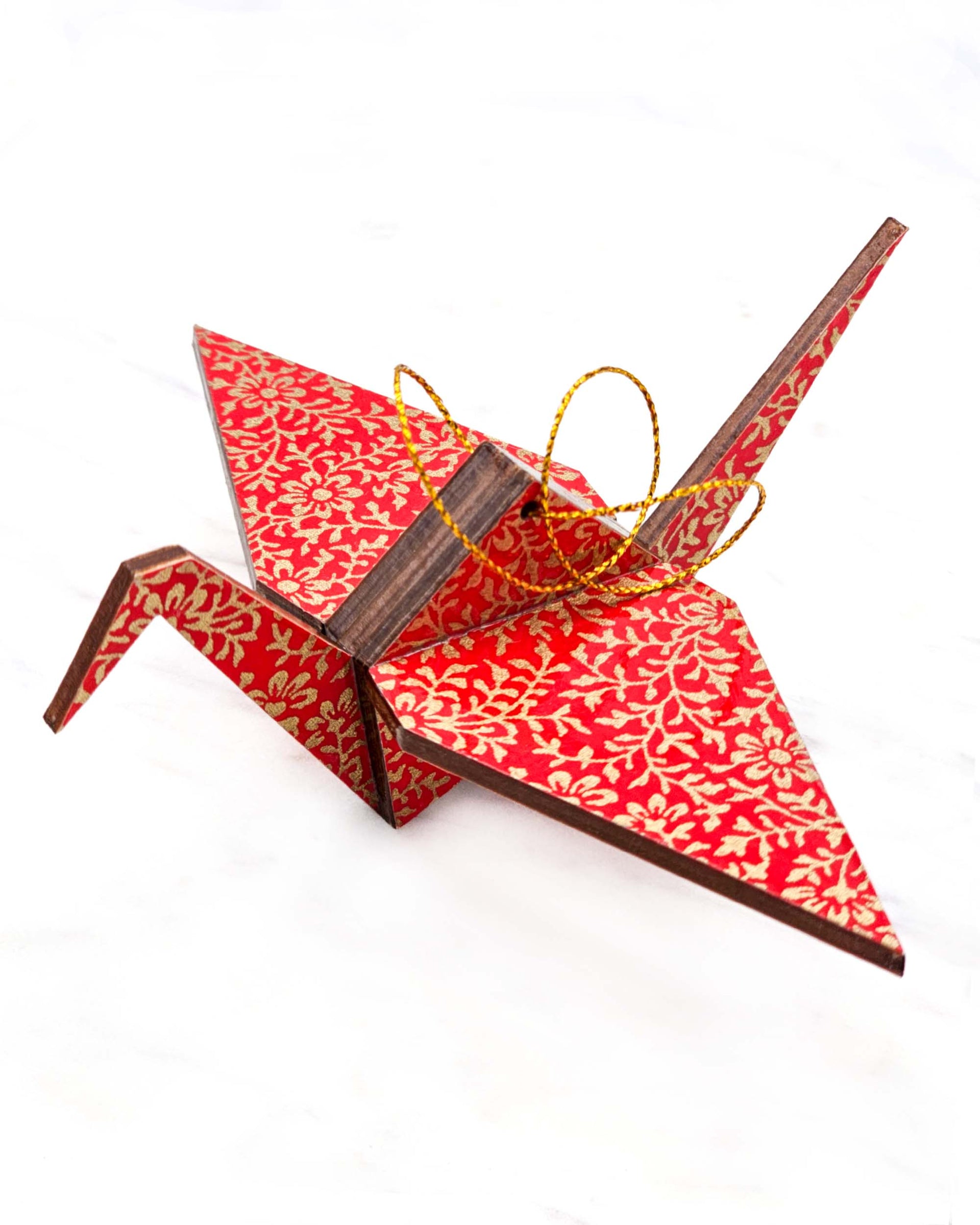 Large wooden origami crane ornament featuring a metallic gold floral motif on a bright red background.