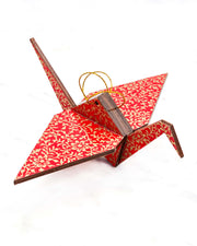 Large wooden origami crane ornament featuring a metallic gold floral motif on a bright red background.