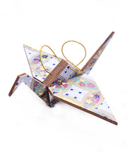 Large wooden origami crane ornament featuring a blue, yellow, and purple shippo design filled with assorted floral and geometric designs on a light purple background with metallic gold details.