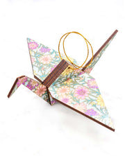 Large wooden origami crane ornament featuring pink, purple, and yellow flowers with green stems on a light blue background with metallic gold accents.