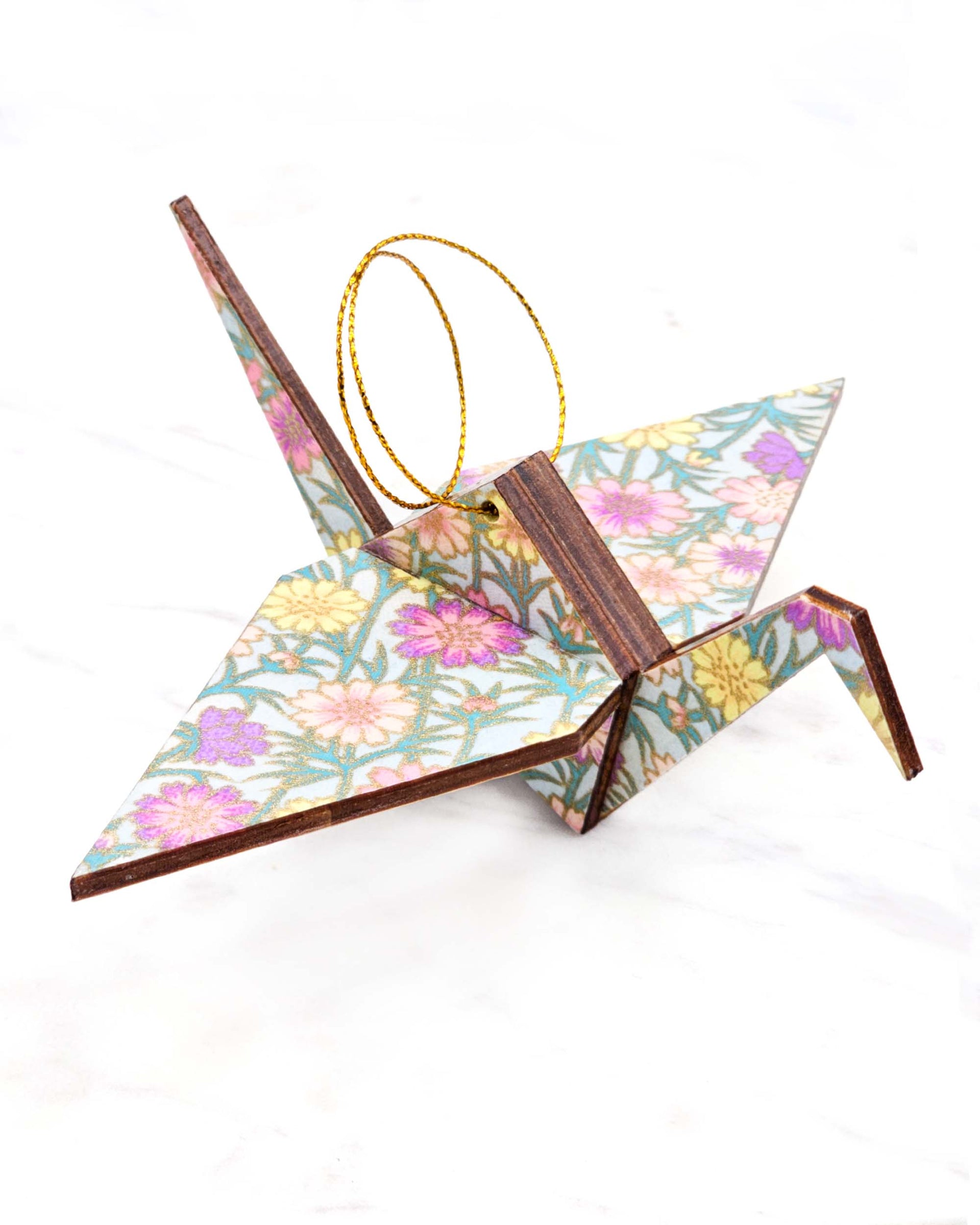 Large wooden origami crane ornament featuring pink, purple, and yellow flowers with green stems on a light blue background with metallic gold accents.