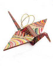 Large wooden origami crane ornament featuring colorful rolling hills in red, yellow, green, black, and gray with metallic gold details.