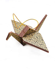 Small wooden origami crane ornament featuring a black traditional Japanese sayagata design on a metallic gold background.