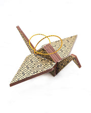 Small wooden origami crane ornament featuring a black traditional Japanese sayagata design on a metallic gold background.