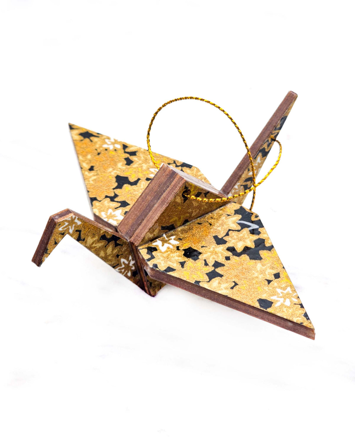 Small wooden origami crane ornament featuring small metallic gold and white momiji (maple leaves) on a black background.